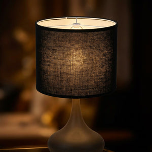 Abat-jour tambour tissu lin noir sur lampe de table avec lumière dorée allumée