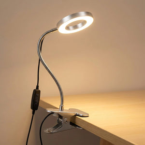 Lampe de bureau à pince argentée avec bras flexible col de cygne allumée