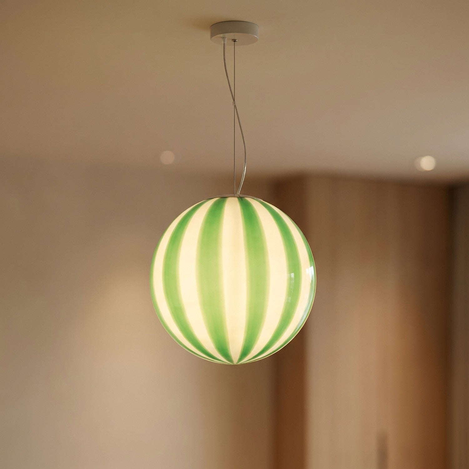 Suspension boule en verre verte à rayures verticales allumée