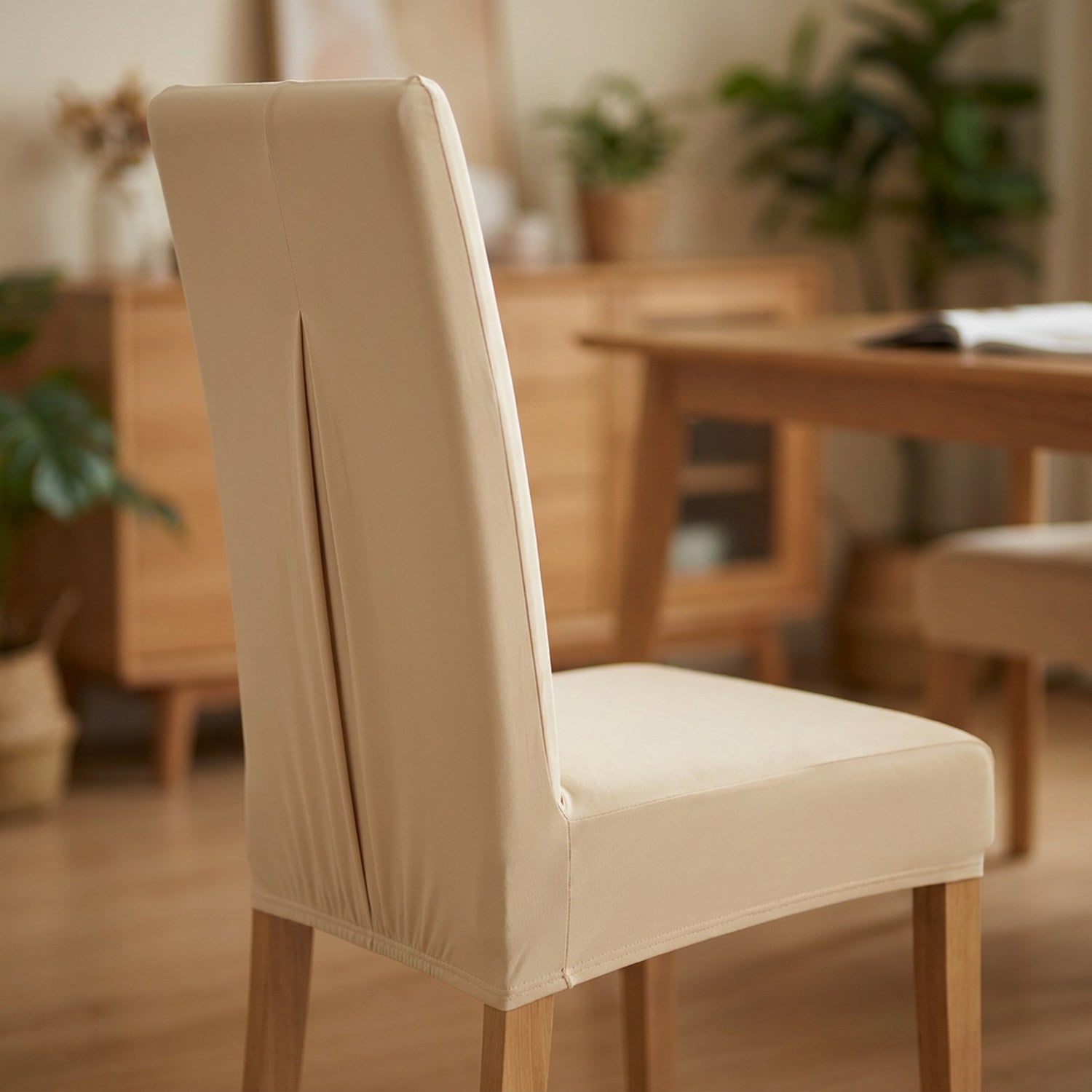 Housse de chaise beige extensible et imperméable sur une chaise de salle à manger