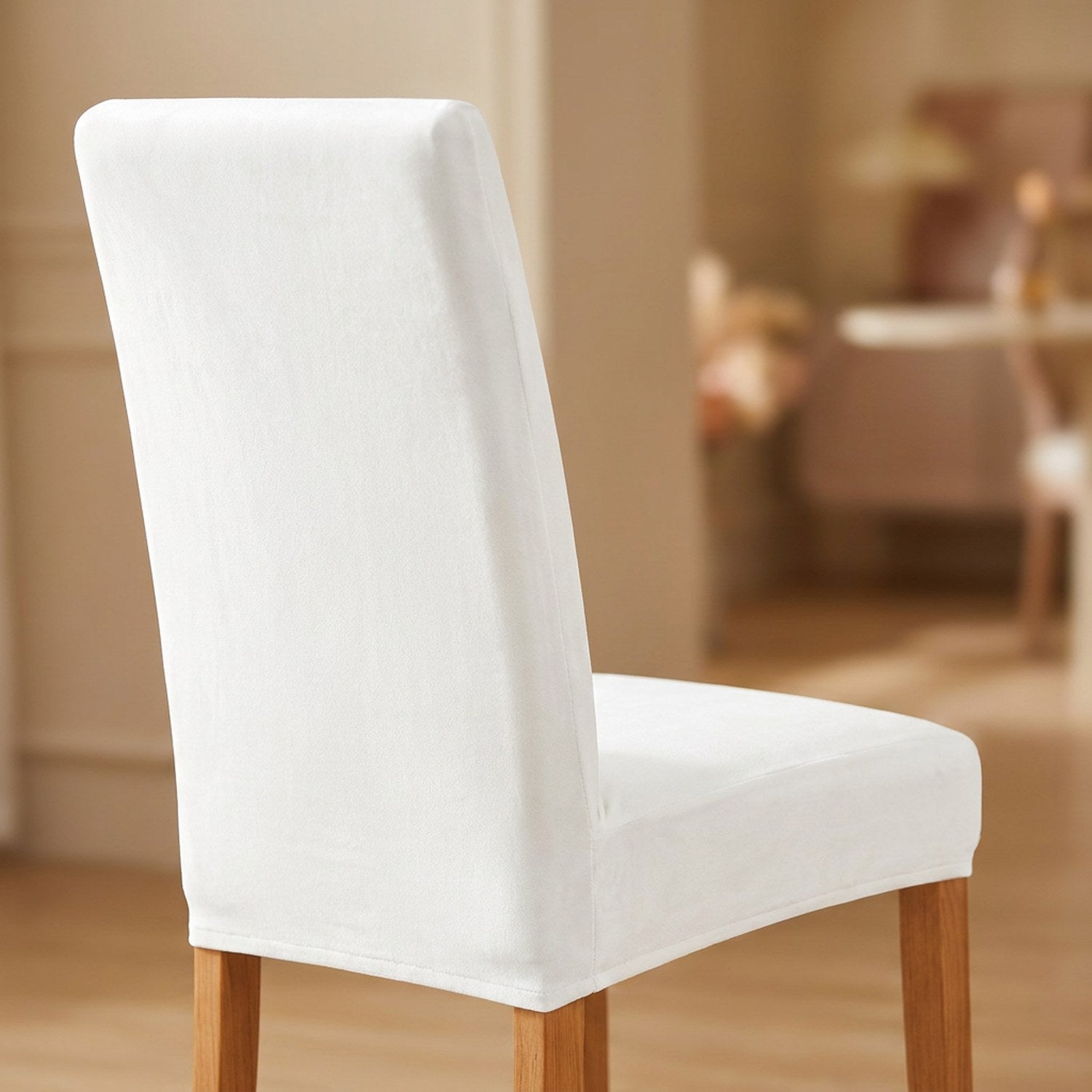 Housse de chaise blanche en velours moelleux sur une chaise de salle à manger