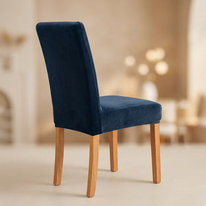 Housse de chaise bleu foncé en velours moelleux sur une chaise de salle à manger