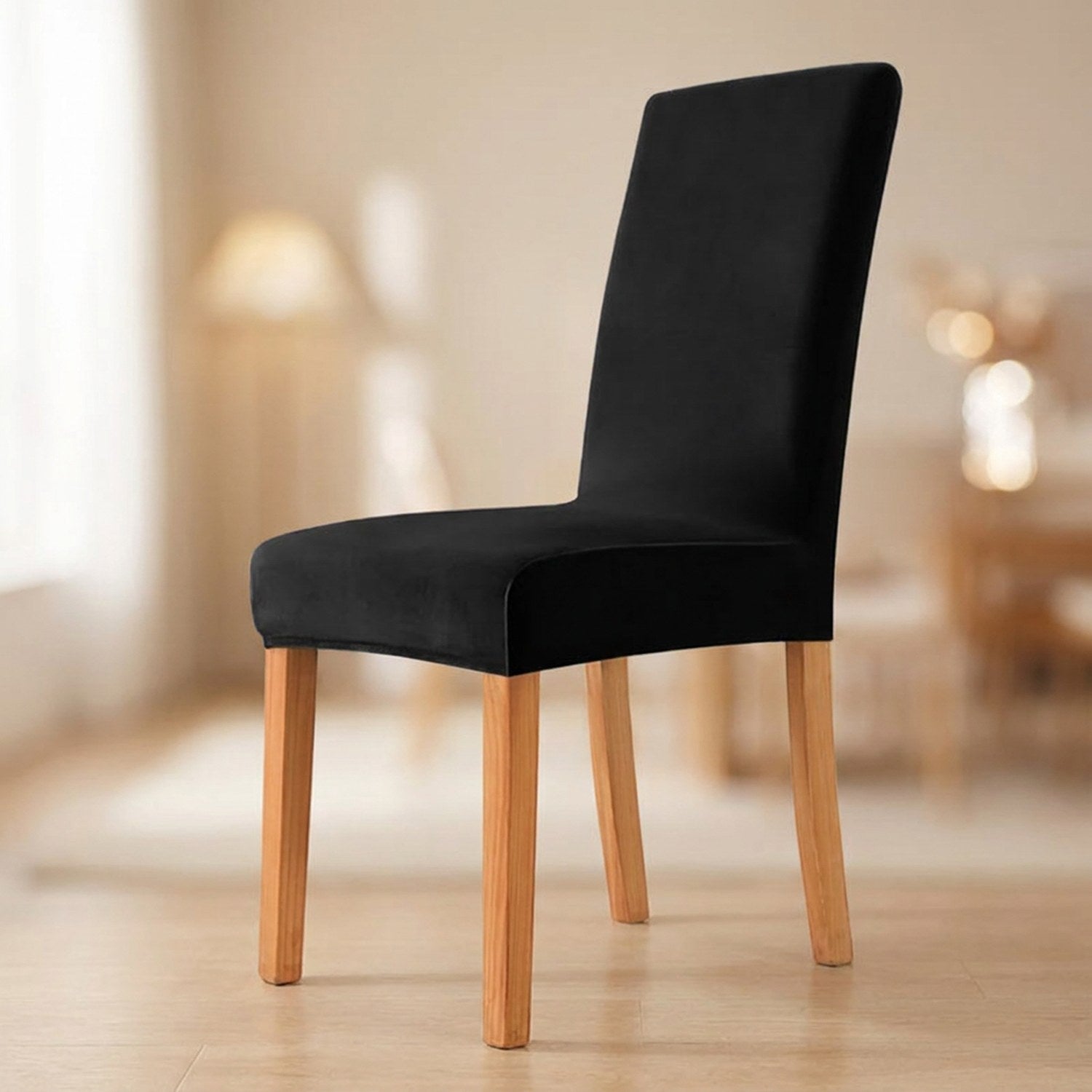 Housse de chaise noire en velours moelleux sur une chaise de salle à manger