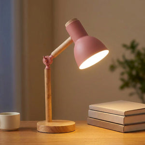 Lampe de bureau articulée en bois avec tête rose allumée sur un bureau