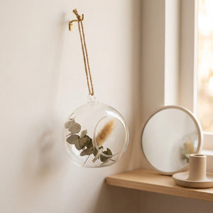 Vase boule en verre transparent suspendu dans un coin chambre avec miroir et étagère en bois