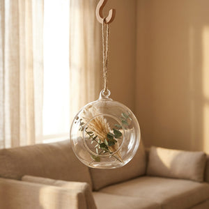 Vase boule en verre suspendu dans un salon scandinave avec canapé lin et rideaux de lin