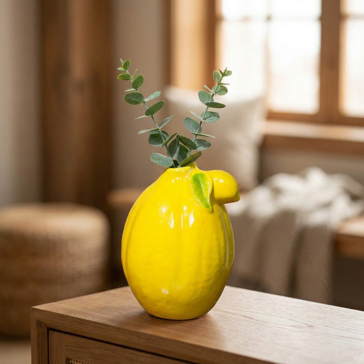 Vase citron jaune sur une console avec des branches d'eucalyptus