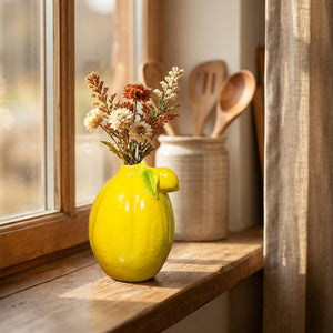 Vase citron jaune sur un rebord de fenêtre de cuisine avec des fleurs séchées