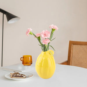 Vase citron céramique avec œillets roses sur table