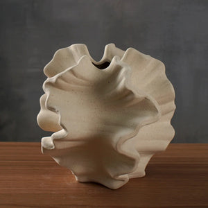 Vase corail en céramique beige mate avec bords ondulés sur surface en bois