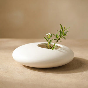 Vase galet en céramique blanche en gros plan sur fond chaleureux