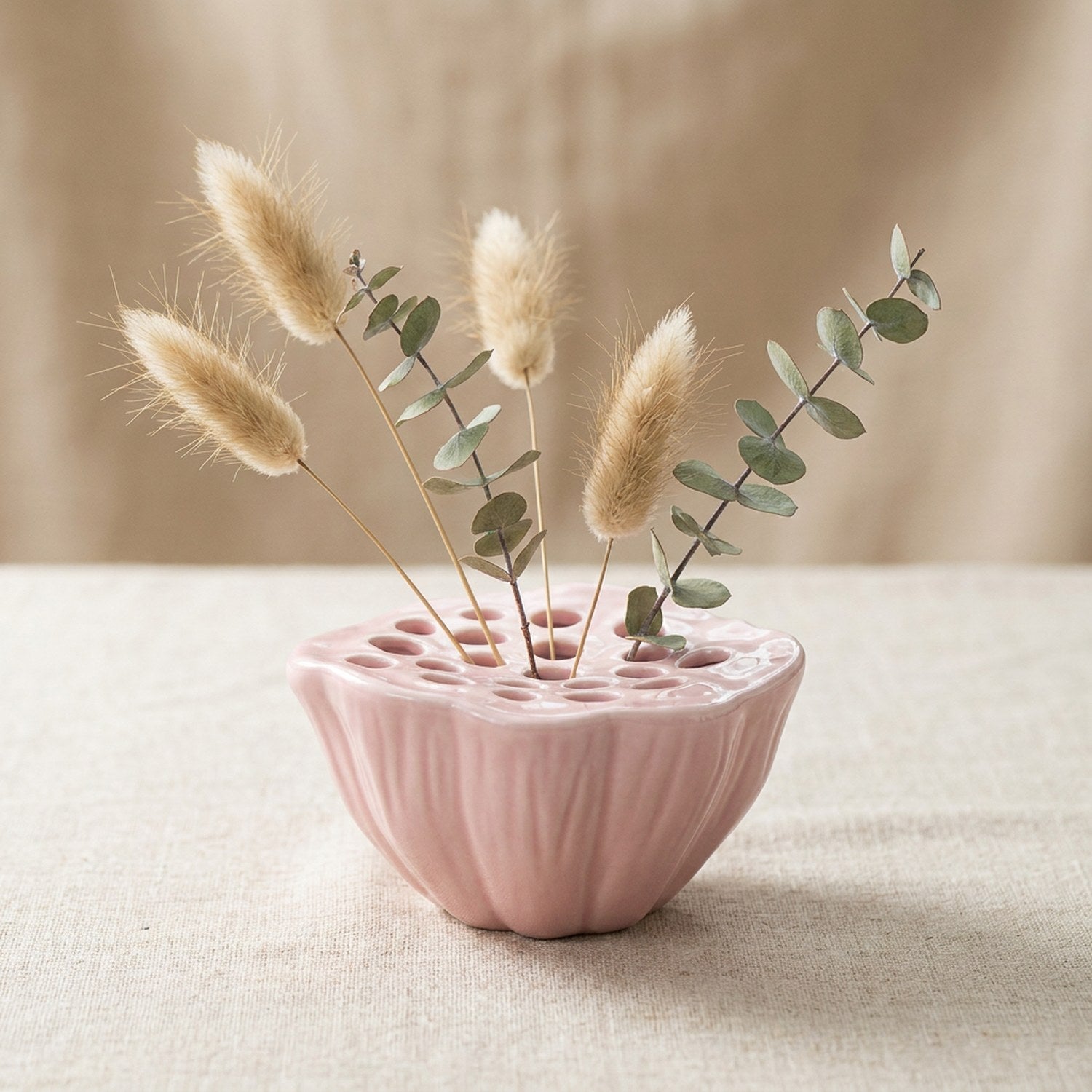 Vase Ikebana en céramique rose en forme de graine de lotus avec pampas sur surface en lin
