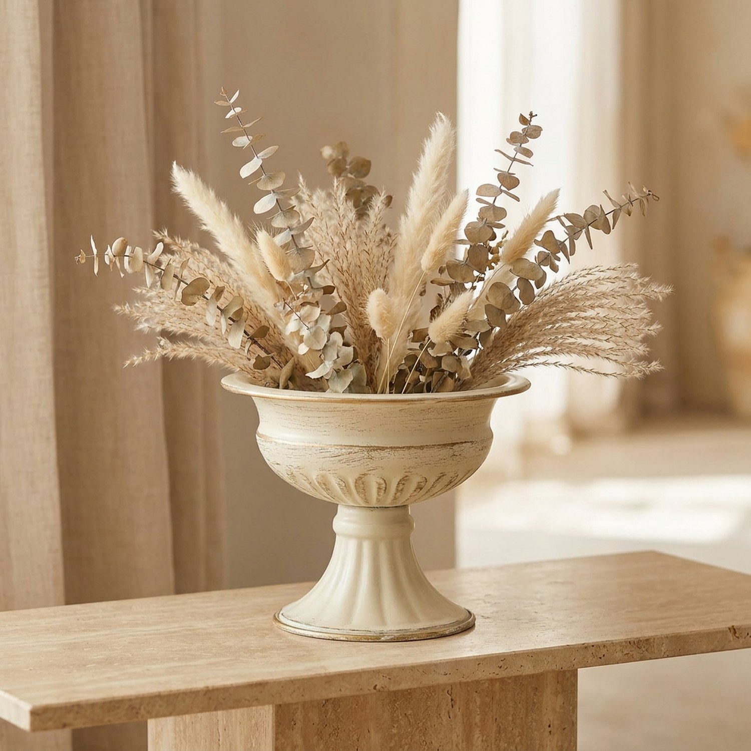 Vase médicis vintage en métal crème et doré garni d'eucalyptus séché sur une table de réception lumineuse