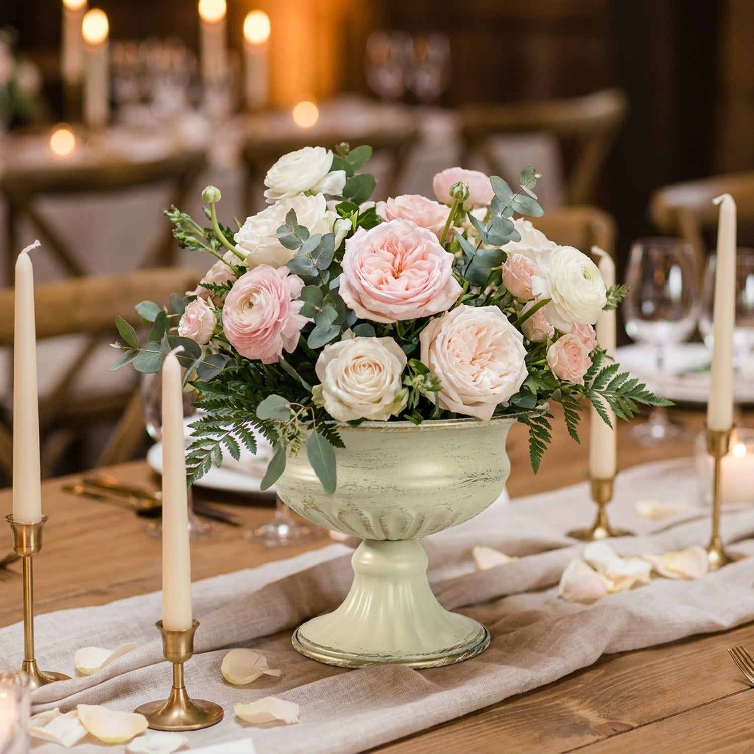 Vase médicis garni de roses sur une table de réception aux chandelles