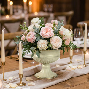 Vase médicis garni de roses sur une table de réception aux chandelles
