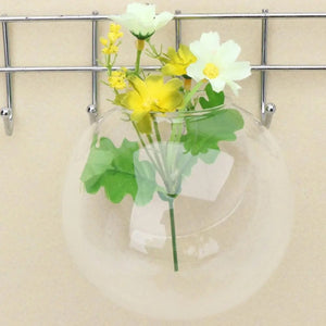 Vase mural en verre suspendu à une grille métal avec fleurs séchées