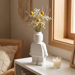 Vase robot blanc avec bouquet de fleurs séchées et lavande dans une bibliothèque scandinave