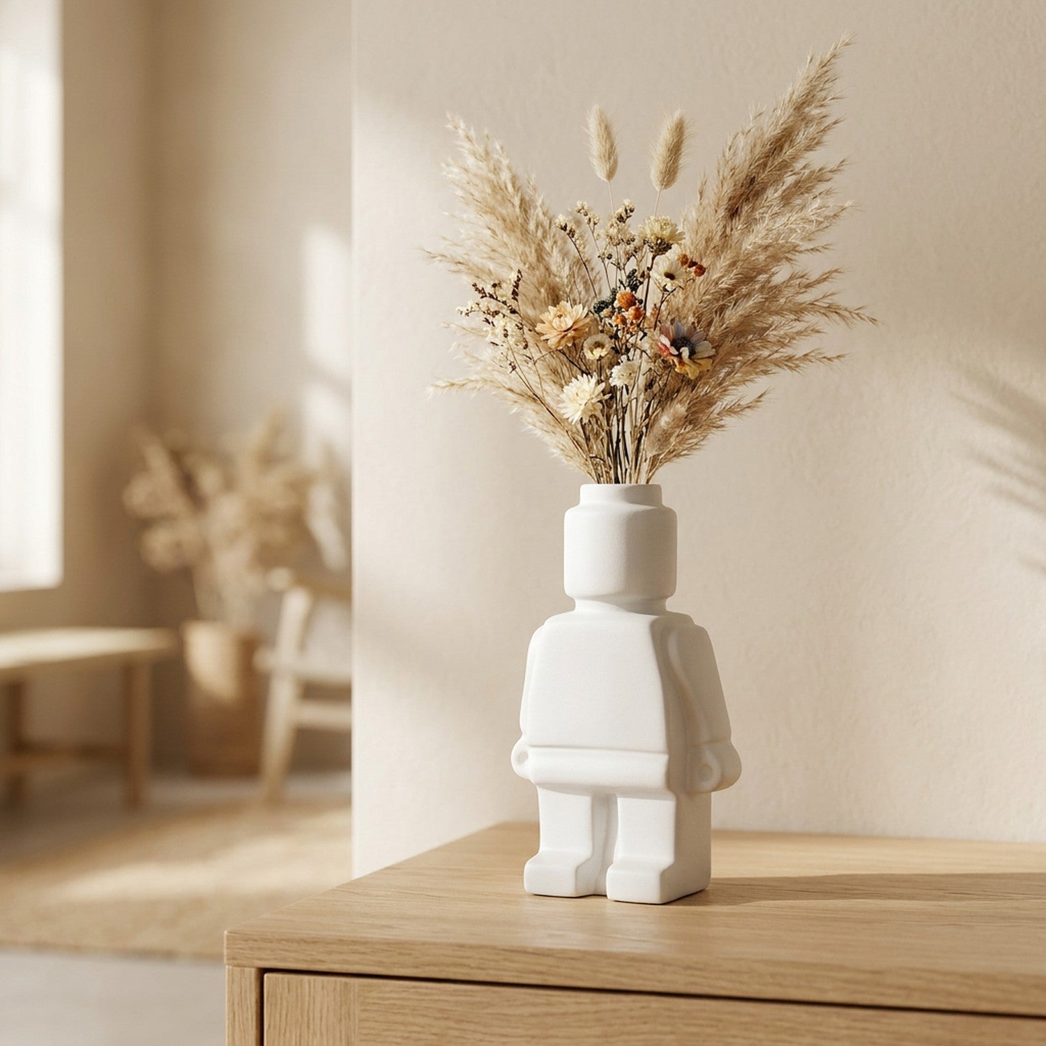 Vase robot en céramique blanc avec fleurs séchées et pampa sur table en bois nordique