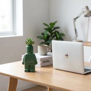 Vase robot sur bureau à côté d'un ordinateur et livres dans espace de travail