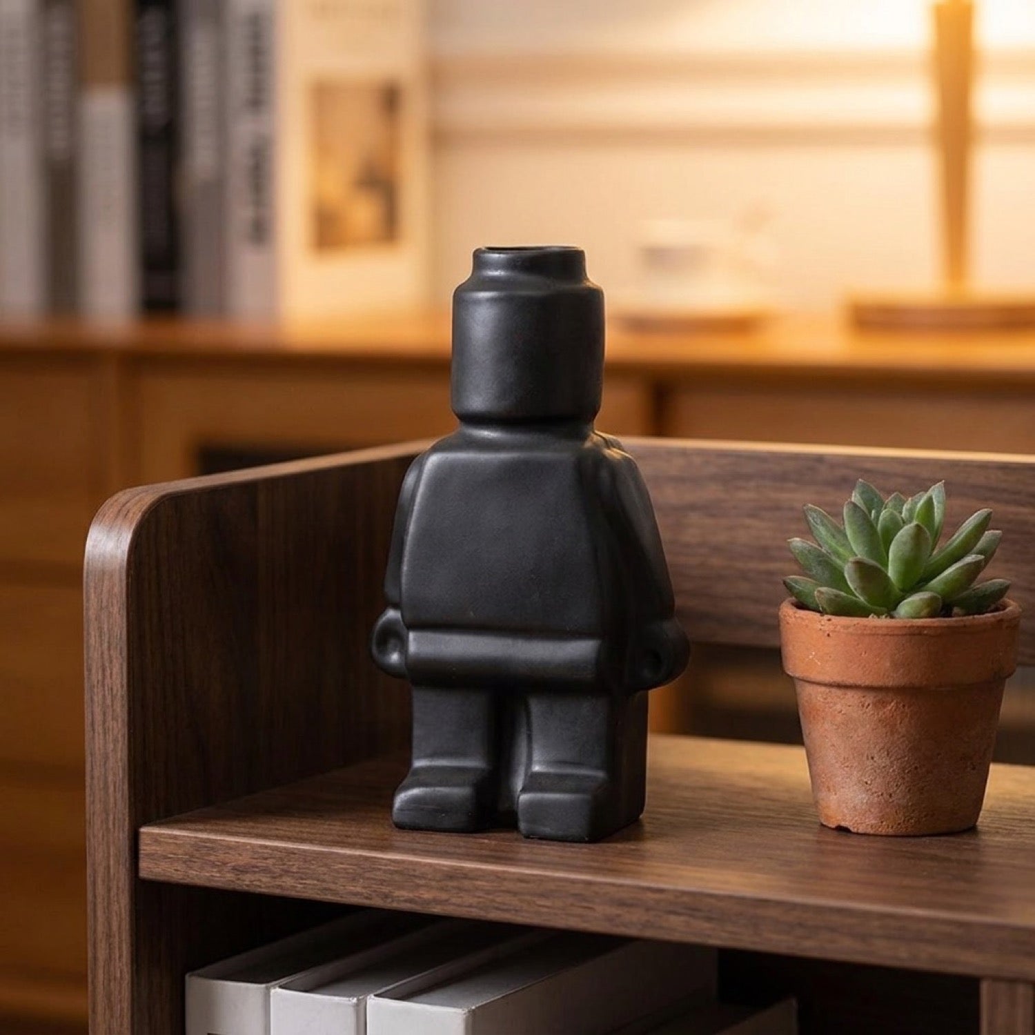 Vase robot céramique noir mat sur étagère en bois foncé avec succulent