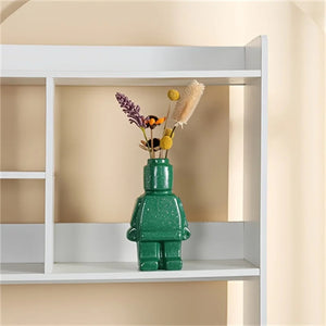 Vase robot vert avec bouquet de fleurs séchées posé dans une étagère blanche