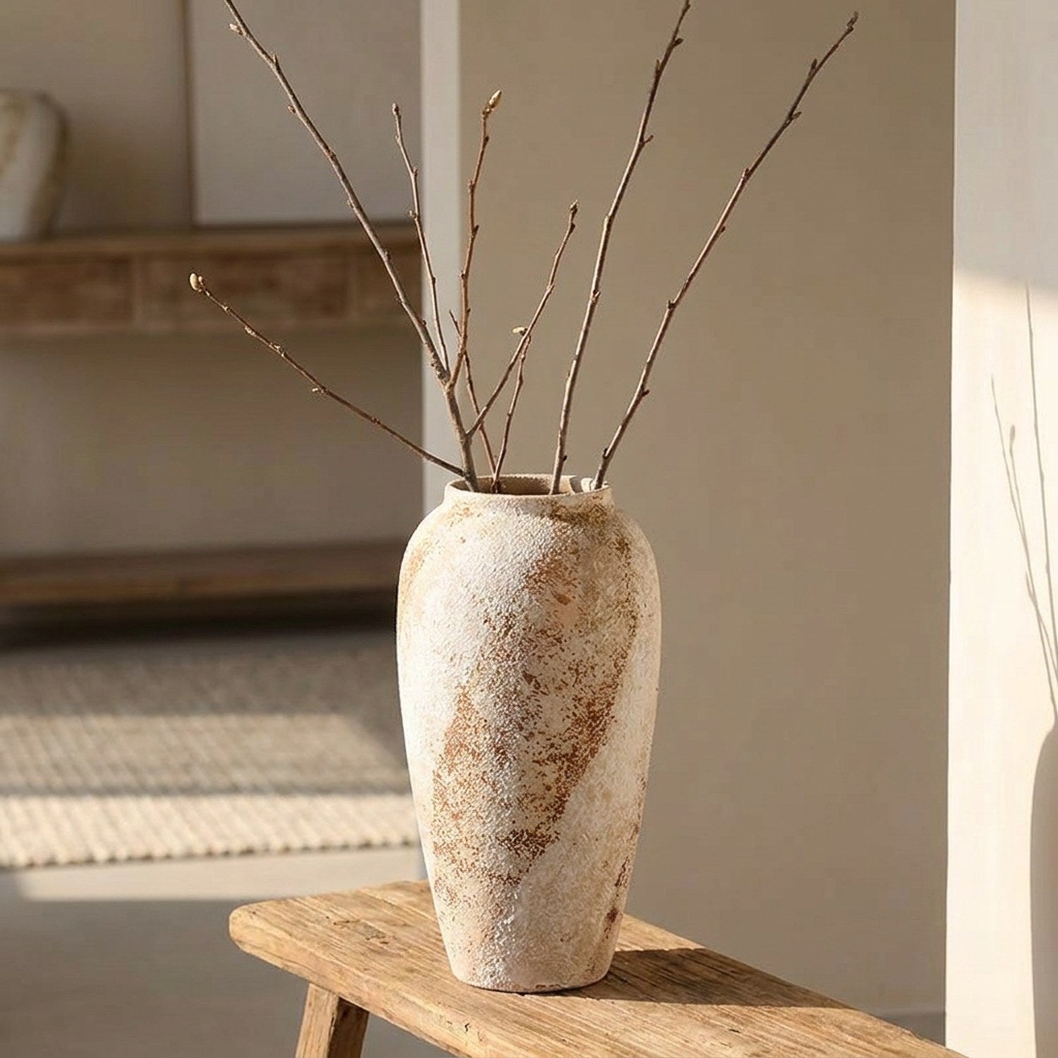 Vase en céramique wabi sabi haut avec branches nues dans une entrée lumineuse