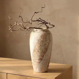 Vase en céramique wabi sabi haut au grès brut moucheté garni de branches séchées sur un buffet en bois