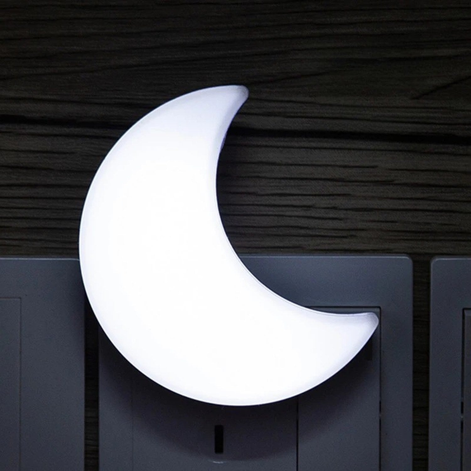 Veilleuse lune allumée en lumière blanche branchée sur une prise murale