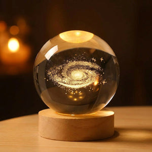 Lampe boule de cristal motif galaxie 3D allumée sur socle en bois