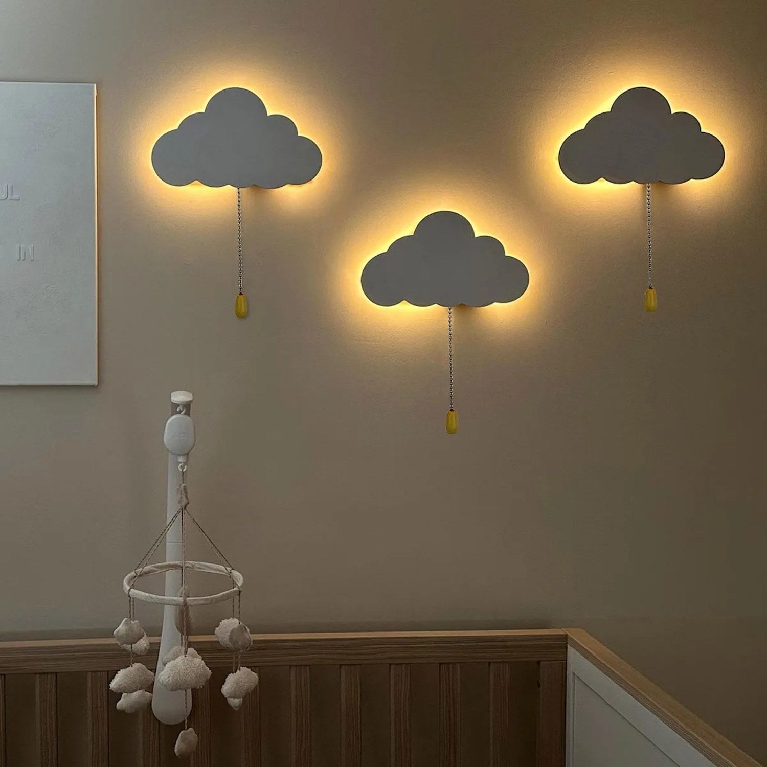 Trois veilleuses murales nuage allumées sur un mur avec halo lumineux chaud