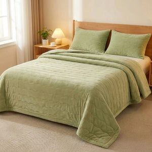 Couvre-lit matelassé uni vert sauge posé sur un lit dans une chambre naturelle