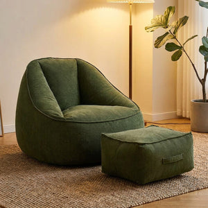 Fauteuil pouf en velours côtelé vert forêt avec repose-pieds dans un coin lecture cosy