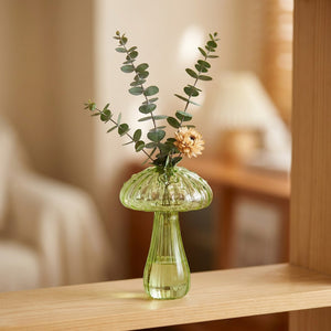 Vase champignon en verre vert avec eucalyptus et fleur séchée sur une étagère