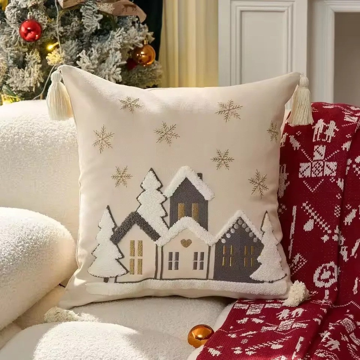 Housse de coussin brodée d'un village enneigé sur canapé décoré de Noël