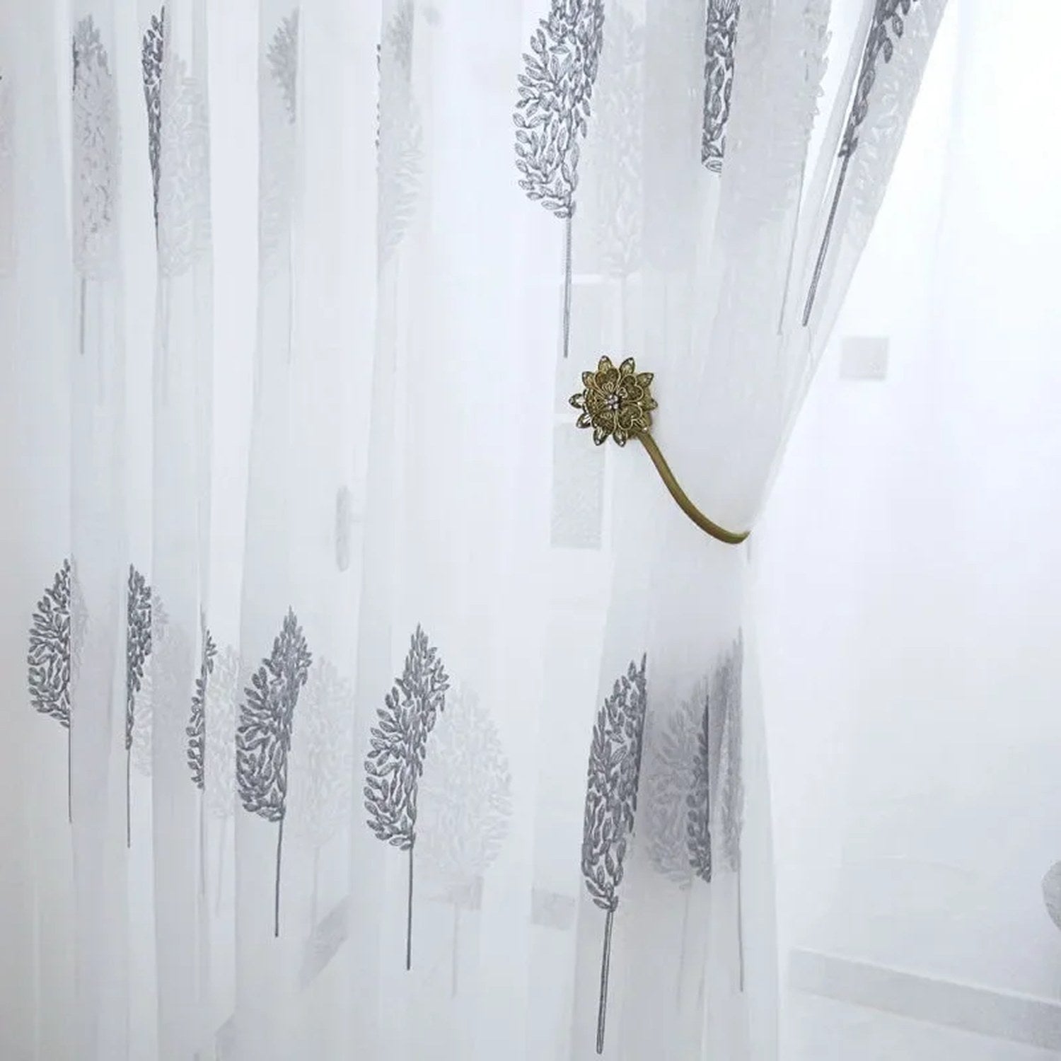 Voilage en tulle blanc retenu par une embrasse fleur dorée