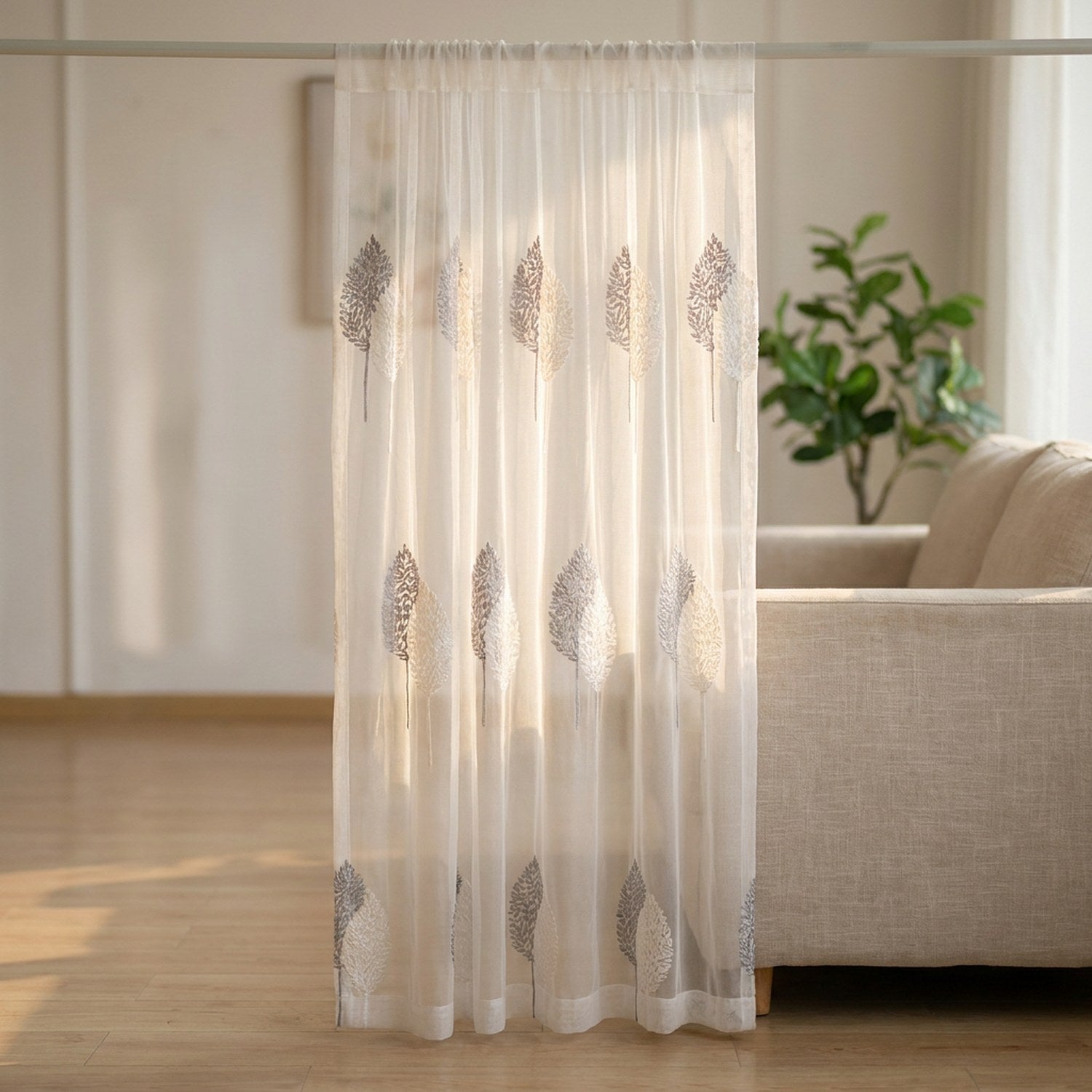 Voilage en tulle blanc au motif d'arbres brodé suspendu à une fenêtre lumineuse d'un salon