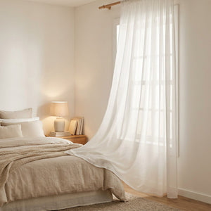 Voilage blanc uni translucide à la fenêtre d'une chambre à coucher lumineuse