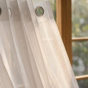 Gros plan sur l'œillet métallique et le tissu tulle du voilage blanc