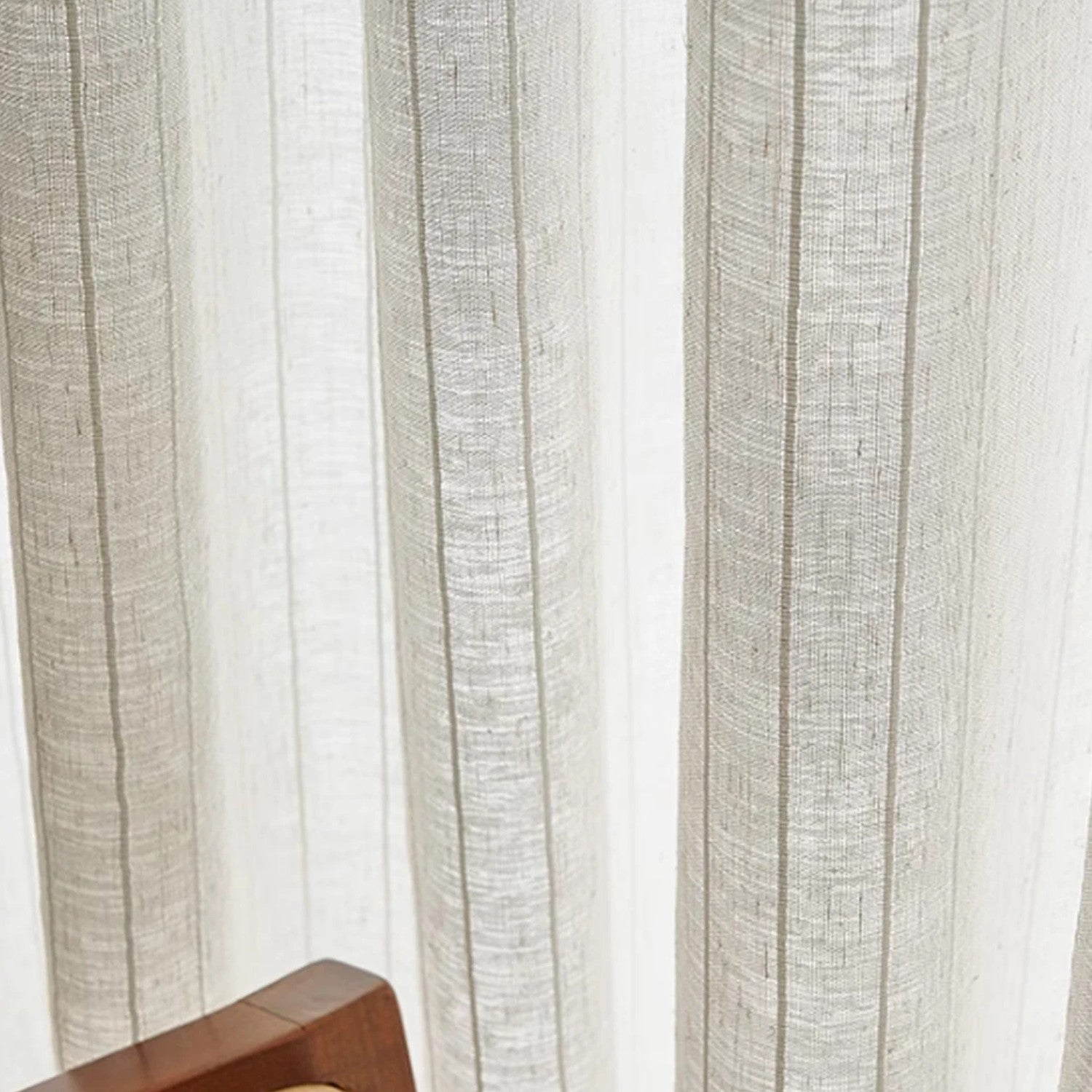 Détail du voilage beige à rayures verticales suspendu devant la lumière