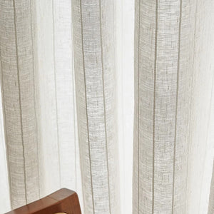 Détail du voilage beige à rayures verticales suspendu devant la lumière