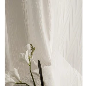 Gros plan sur les fins plis du tissu voilage blanc près d'une fleur blanche