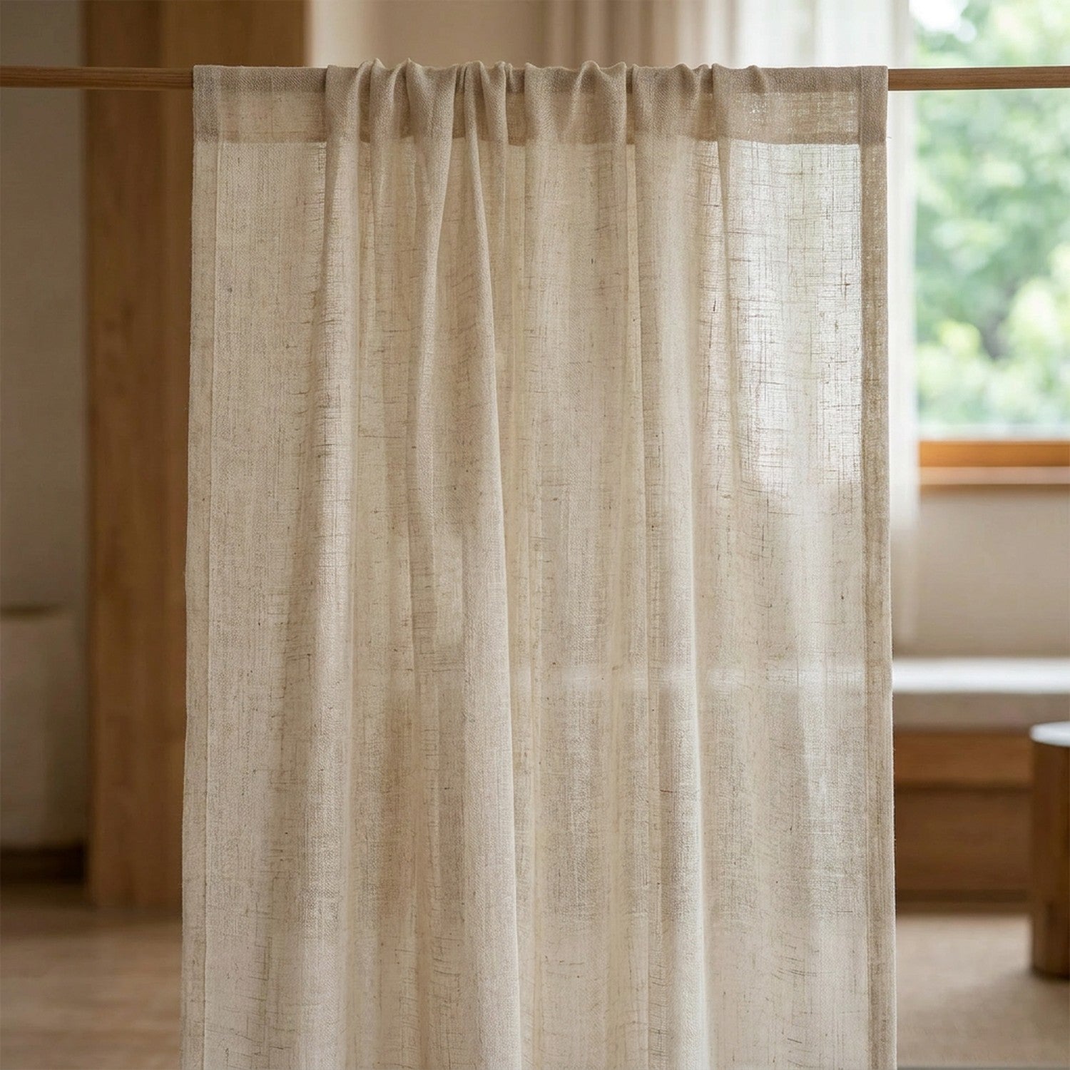 Voilage tamisant à l'aspect lin naturel de teinte écru suspendu à une fenêtre dans une chambre lumineuse et chaleureuse