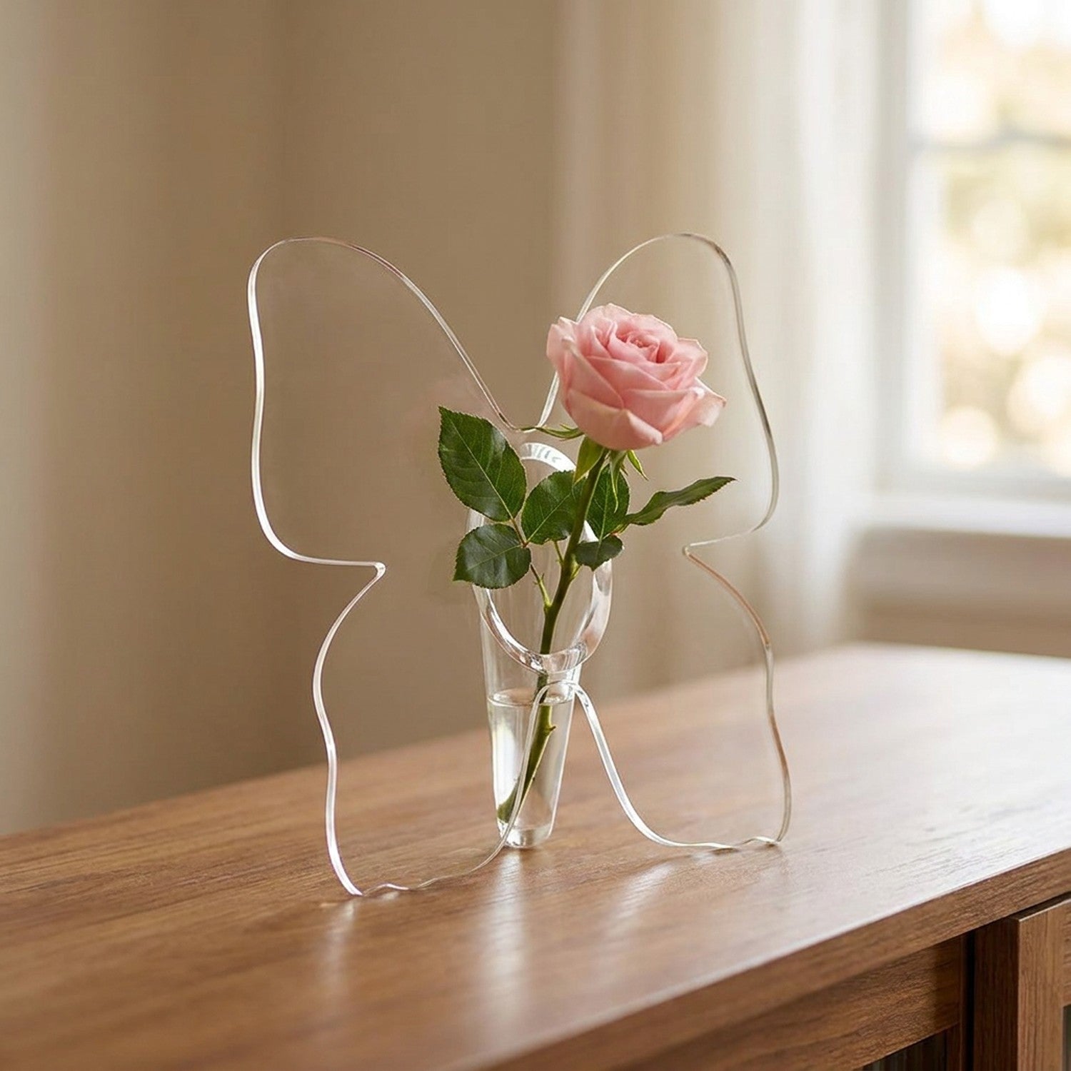 Vase à fleurs en acrylique transparent en forme de papillon avec une rose posé sur une console en bois