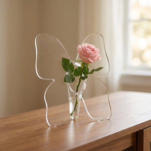 Vase à fleurs en acrylique transparent en forme de papillon avec une rose posé sur une console en bois