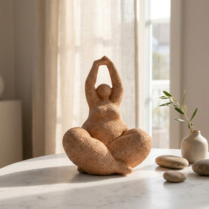 Figurine femme yoga en résine style poterie sur surface marbre avec lumière naturelle